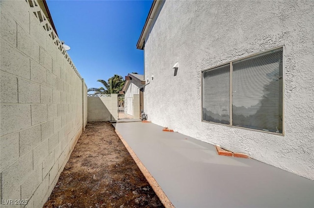 view of side of property featuring fence, a gate, and stucco siding