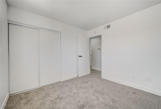 unfurnished bedroom featuring carpet floors, a closet, visible vents, and baseboards