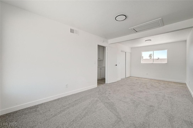 carpeted spare room featuring visible vents and baseboards