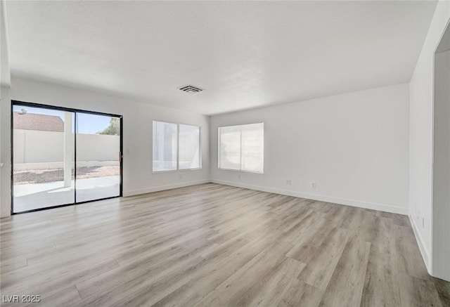 unfurnished room with light wood-style floors, visible vents, and plenty of natural light