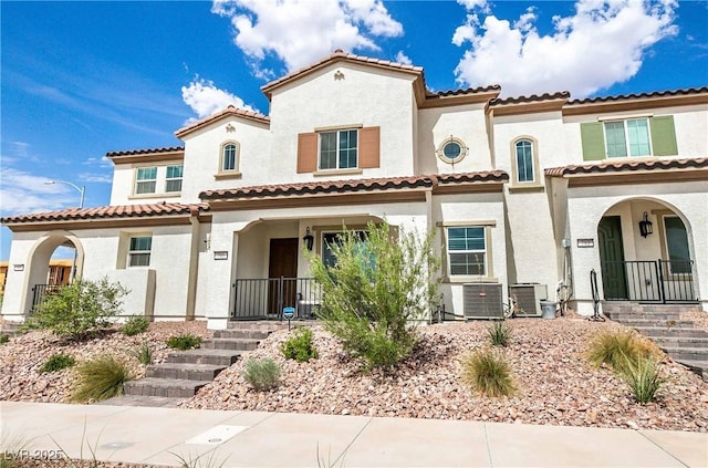 mediterranean / spanish home featuring covered porch, stucco siding, and central AC unit