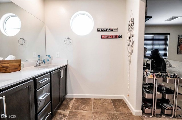 bathroom with visible vents, a sink, baseboards, and double vanity