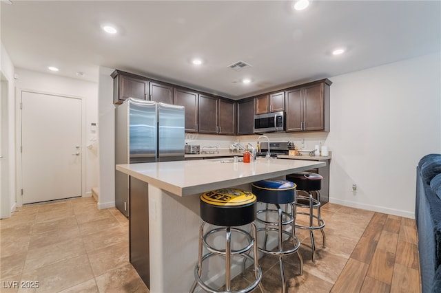 kitchen featuring recessed lighting, light countertops, visible vents, appliances with stainless steel finishes, and dark brown cabinets