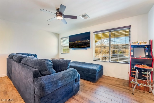 living area with visible vents, ceiling fan, baseboards, and wood finished floors