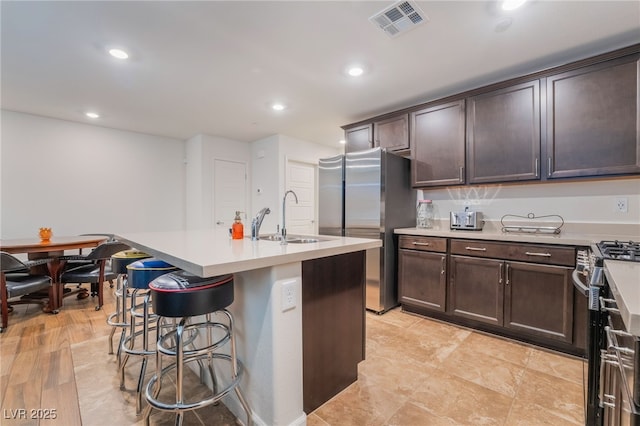 kitchen featuring appliances with stainless steel finishes, visible vents, a sink, and dark brown cabinets