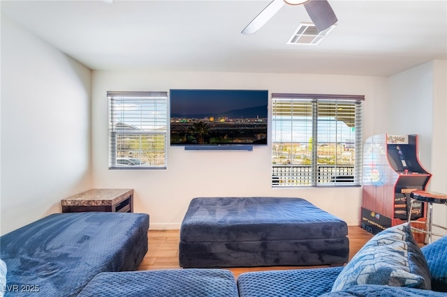 living area featuring ceiling fan, visible vents, a wealth of natural light, and wood finished floors