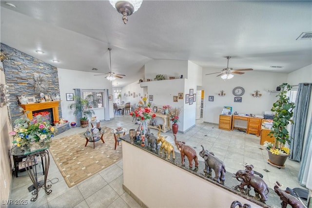 kitchen featuring visible vents, lofted ceiling, a stone fireplace, and ceiling fan