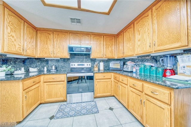 kitchen featuring tasteful backsplash, visible vents, dark stone counters, light tile patterned floors, and stainless steel appliances