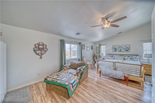 bedroom with light wood-type flooring, visible vents, lofted ceiling, and a textured ceiling