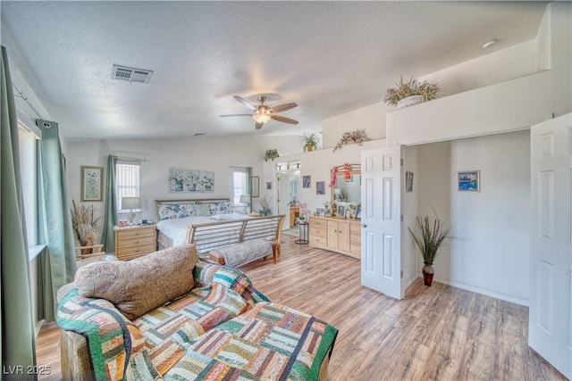 interior space featuring visible vents, light wood-style flooring, a ceiling fan, a textured ceiling, and baseboards