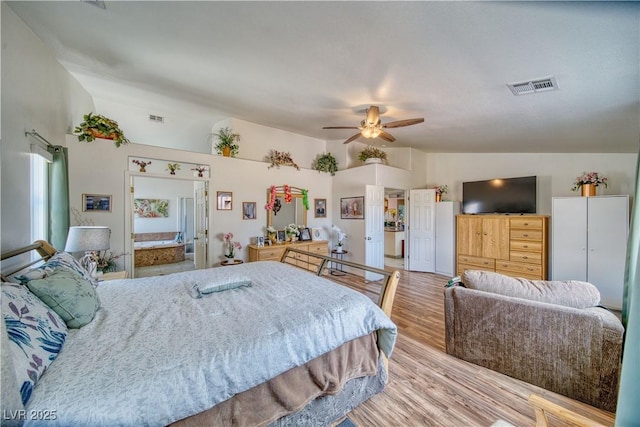 bedroom featuring ensuite bath, lofted ceiling, wood finished floors, and visible vents