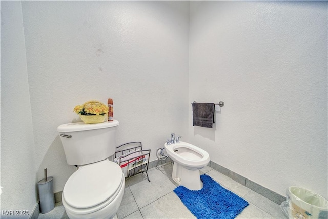 half bath featuring tile patterned floors, baseboards, a bidet, and toilet