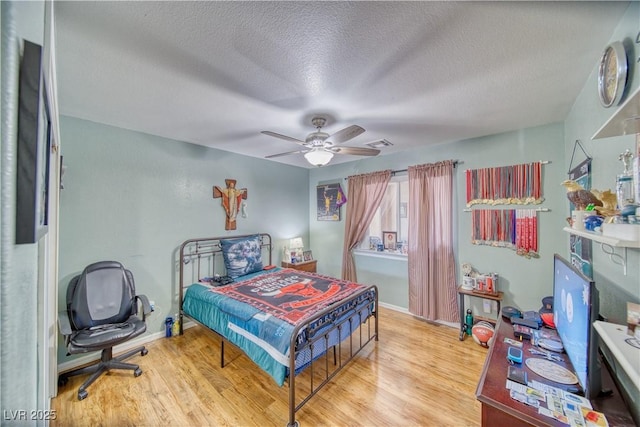 bedroom with visible vents, a textured ceiling, ceiling fan, and wood finished floors