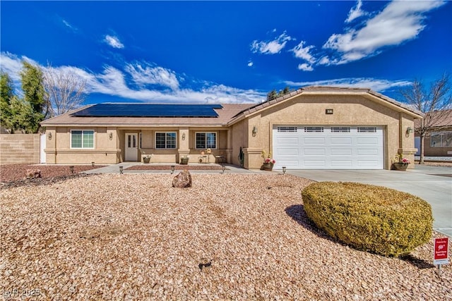 single story home with stucco siding, driveway, fence, an attached garage, and solar panels