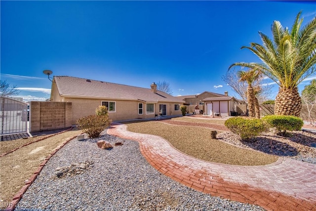 back of property featuring a gate, fence, and stucco siding