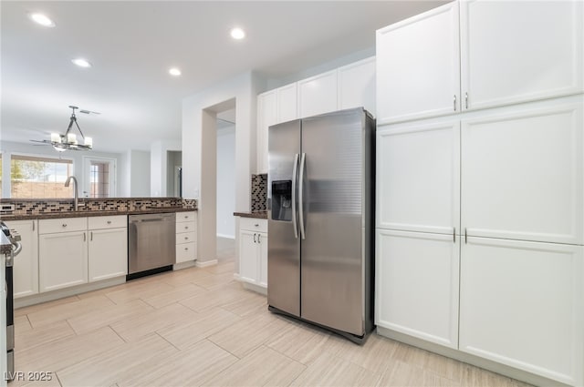 kitchen featuring stainless steel appliances, backsplash, a sink, and white cabinetry