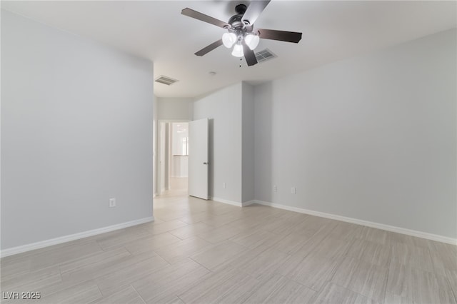 spare room with baseboards, visible vents, and ceiling fan