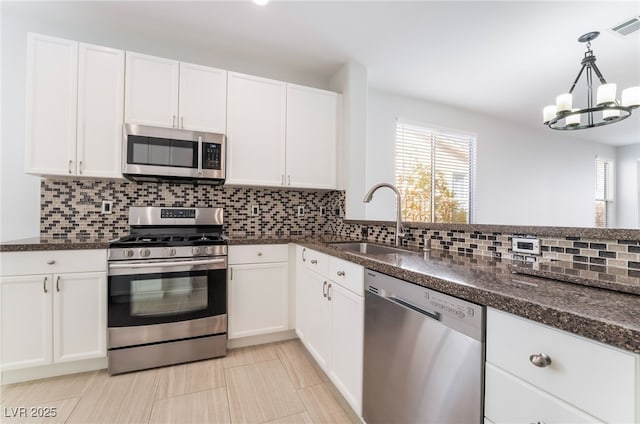 kitchen featuring decorative backsplash, appliances with stainless steel finishes, white cabinets, and a sink