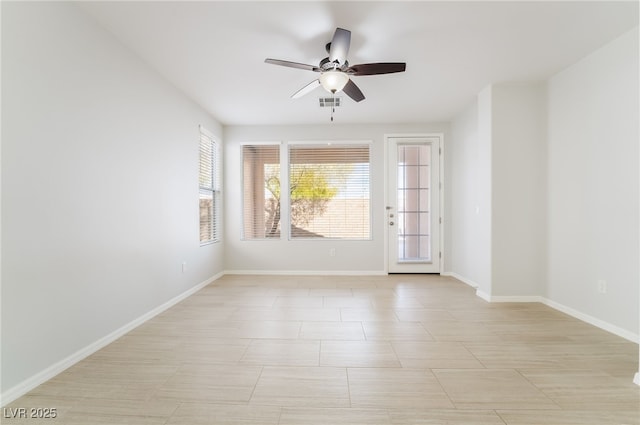 spare room featuring ceiling fan, visible vents, and baseboards