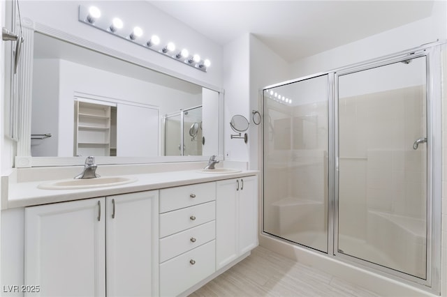 full bathroom featuring double vanity, a sink, and a shower stall