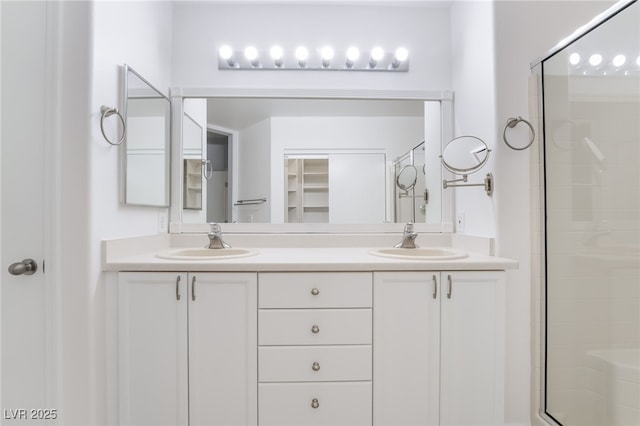 full bath featuring double vanity, a sink, and a shower stall