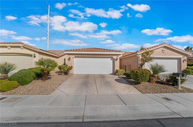 mediterranean / spanish-style house with concrete driveway, a tile roof, an attached garage, and stucco siding