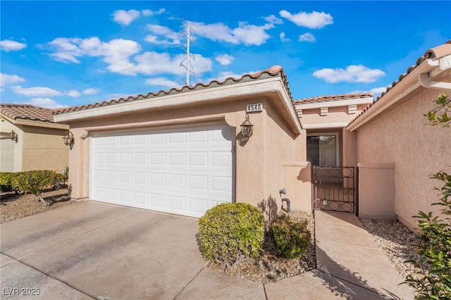 exterior space featuring driveway, an attached garage, a gate, and stucco siding