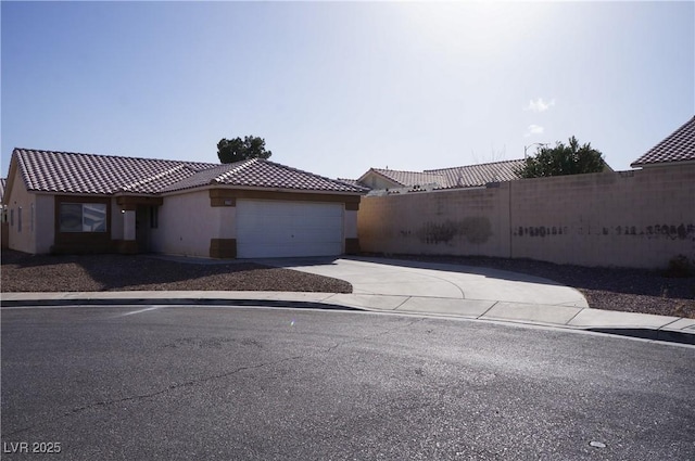 view of front of property featuring driveway, a tiled roof, an attached garage, fence, and stucco siding