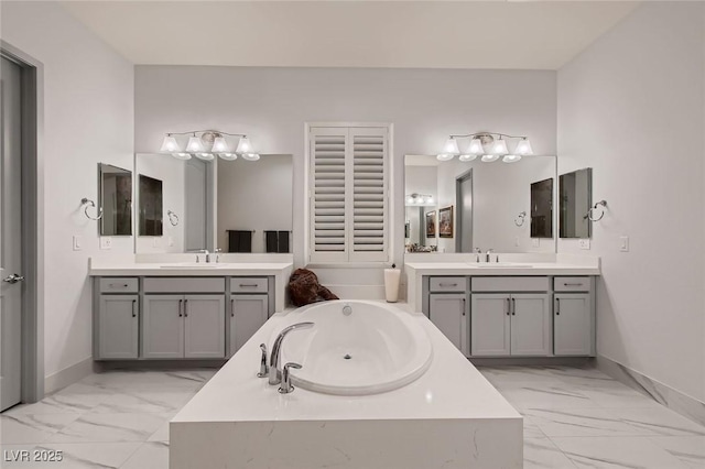 full bath with marble finish floor, a sink, a bath, and baseboards