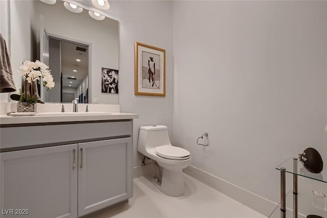 bathroom featuring toilet, baseboards, and vanity