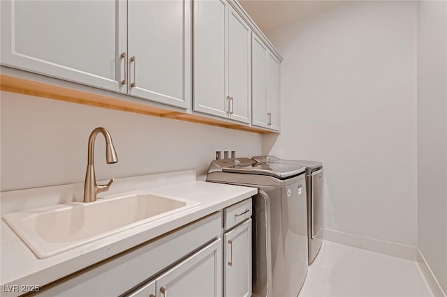 laundry room featuring washer and clothes dryer, cabinet space, a sink, baseboards, and tile patterned floors