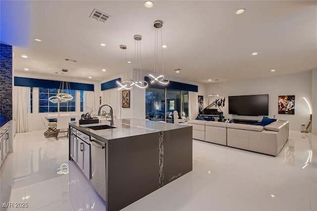 kitchen featuring visible vents, dishwasher, a kitchen island with sink, a sink, and recessed lighting