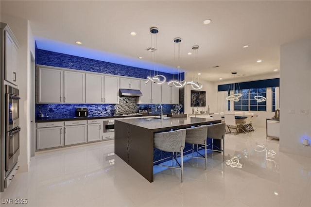 kitchen with a kitchen bar, dark countertops, stainless steel appliances, decorative backsplash, and hanging light fixtures