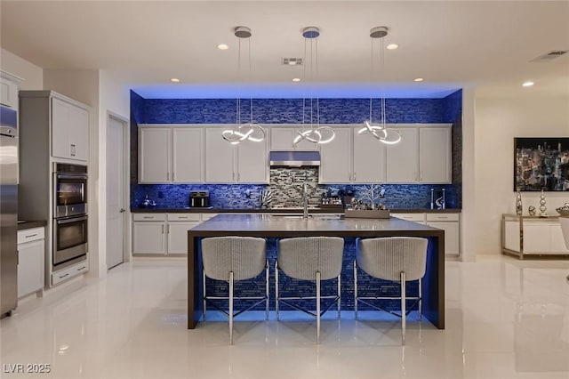 kitchen with under cabinet range hood, visible vents, appliances with stainless steel finishes, and dark countertops