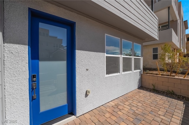 view of exterior entry featuring a patio and stucco siding