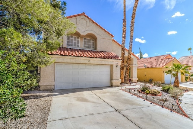 mediterranean / spanish house with a garage, driveway, a tiled roof, and stucco siding