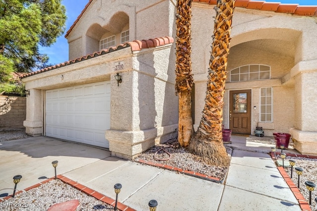 view of exterior entry featuring concrete driveway, a tile roof, and stucco siding