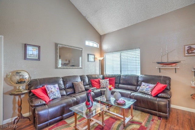 living area featuring high vaulted ceiling, a textured ceiling, baseboards, and wood finished floors