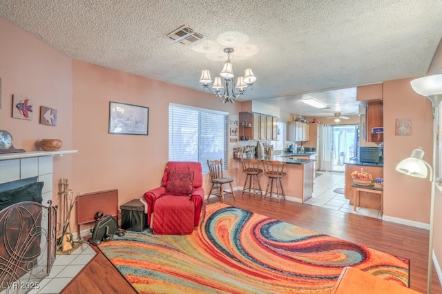 living area featuring light wood-style floors, plenty of natural light, visible vents, and a chandelier