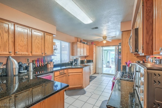 kitchen with visible vents, a ceiling fan, stainless steel microwave, a sink, and light tile patterned flooring