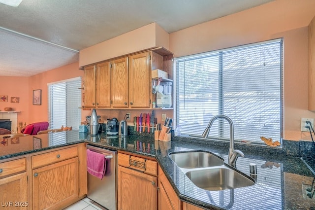 kitchen featuring dishwasher, dark stone countertops, a peninsula, a textured ceiling, and a sink