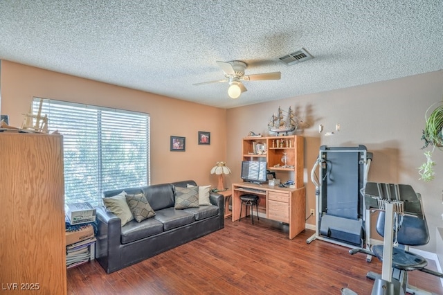 office with a textured ceiling, wood finished floors, visible vents, baseboards, and a ceiling fan