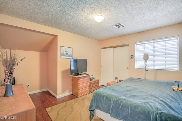 bedroom featuring baseboards, visible vents, wood finished floors, a textured ceiling, and a closet