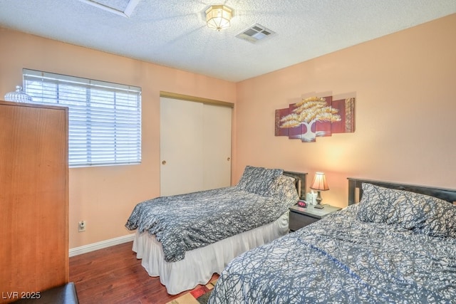 bedroom featuring baseboards, visible vents, wood finished floors, a textured ceiling, and a closet