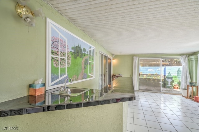 kitchen with tile counters, tile patterned flooring, and a sink