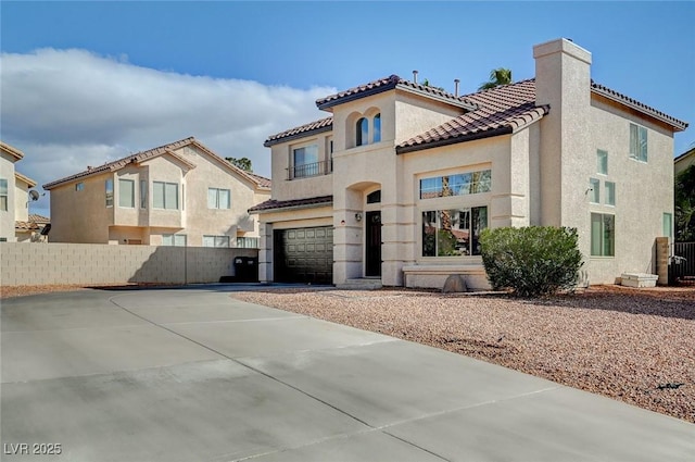 mediterranean / spanish-style home featuring an attached garage, fence, driveway, and stucco siding