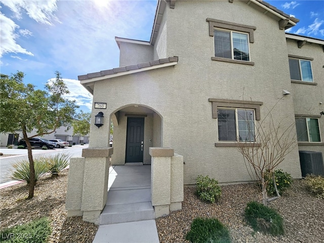 view of front of property with a tiled roof, central AC unit, and stucco siding