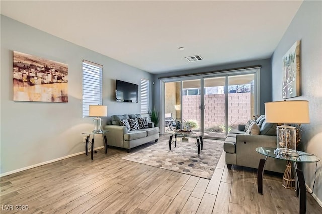 living area with visible vents, baseboards, and wood finished floors