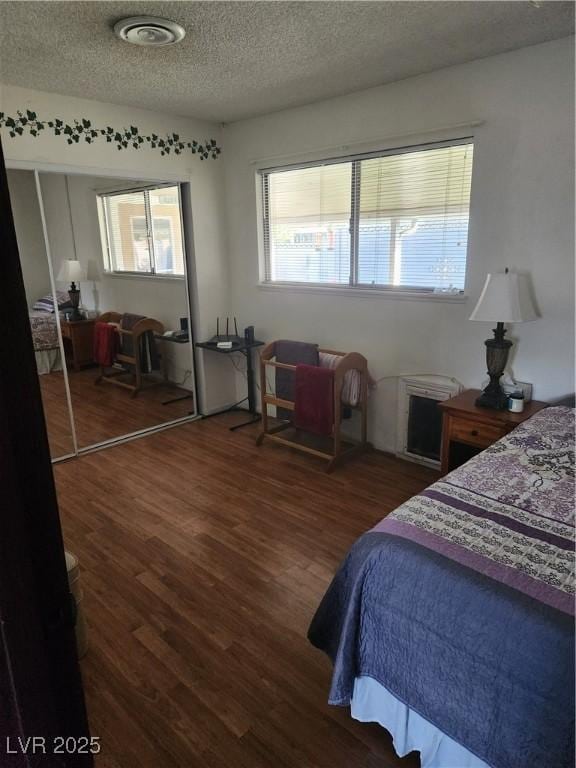 bedroom featuring a textured ceiling, visible vents, and wood finished floors