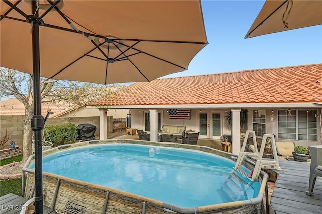 view of pool with french doors, fence, and an outdoor living space